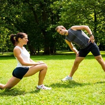 Young man and woman exercising and stretching muscles before sport activity - outdoor in nature